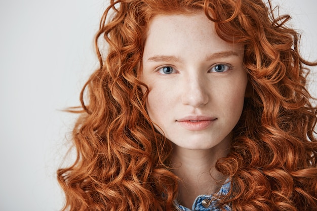 Gros plan de belle fille aux cheveux roux bouclés et taches de rousseur.