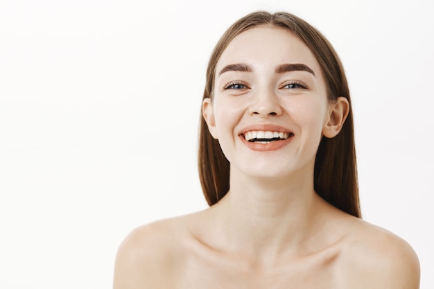 Gros plan de la belle et heureuse jeune femme charmante posant nue en riant et souriant en regardant