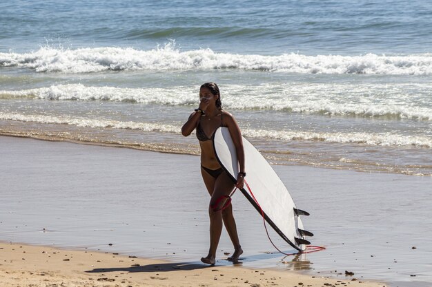 Gros plan d'une belle jeune femme avec une planche de surf sur la plage