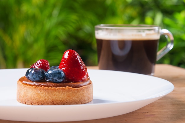 Gros plan d&#39;une belle mini tarte avec des baies et une tasse de café