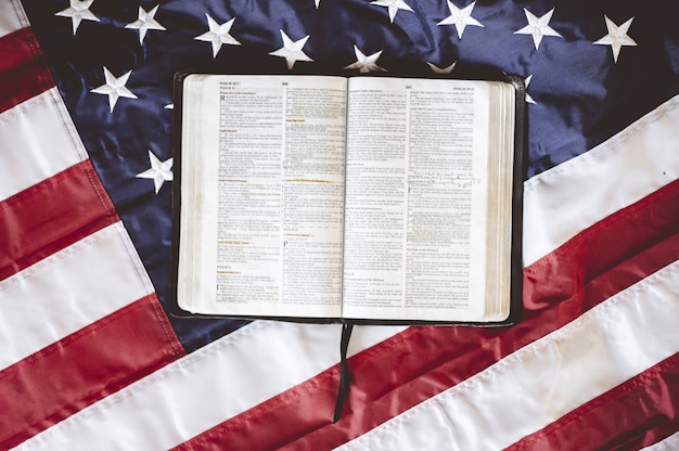 Photo gratuite gros plan de la bible ouverte dans les pages mises sur le drapeau américain - parfait pour prier le concept