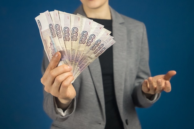 Gros plan sur des billets en rouble russe dans la main d'une femme vêtue d'une veste grise. mise au point sélective.