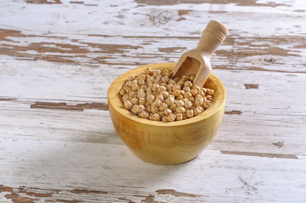 Gros plan d'un bol en bois rustique de pois chiches crus (Cicer arietinum)