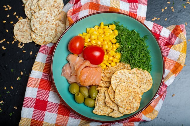 Gros plan d'un bol de salade avec du saumon, des craquelins et des légumes sur une serviette sur la table