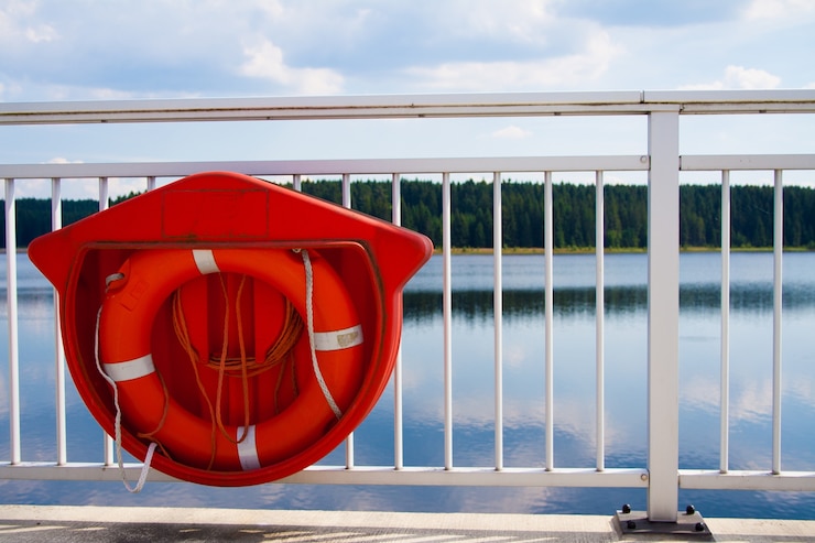 Photo gratuit gros plan d'une bouée de sauvetage rouge pendu sur la balustrade blanche d'un pont