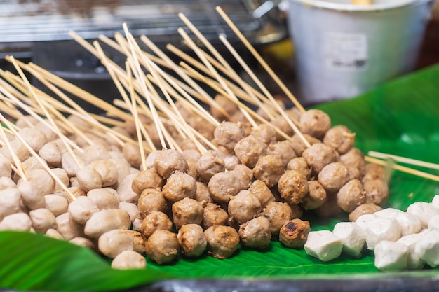 Gros plan des boulettes de viande grillées sur fond de bâtons de bambou, marché thaïlandais de l'alimentation de rue
