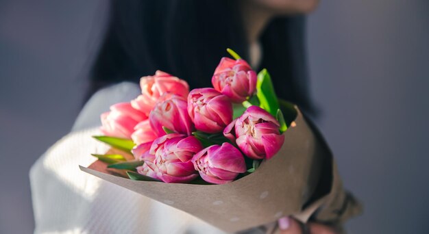 Gros plan sur un bouquet de tulipes roses dans des mains féminines