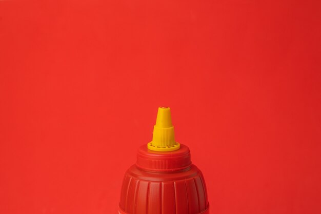 Gros plan d'une bouteille de ketchup rouge sur un mur rouge