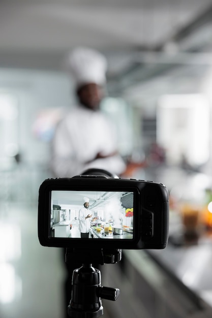 Photo gratuite gros plan sur une caméra enregistrant le chef cuisinier préparant un plat gastronomique pour l'école culinaire dans la cuisine du restaurant. chef cuisinier préparant le dîner tout en filmant la création pour l'école de gastronomie.