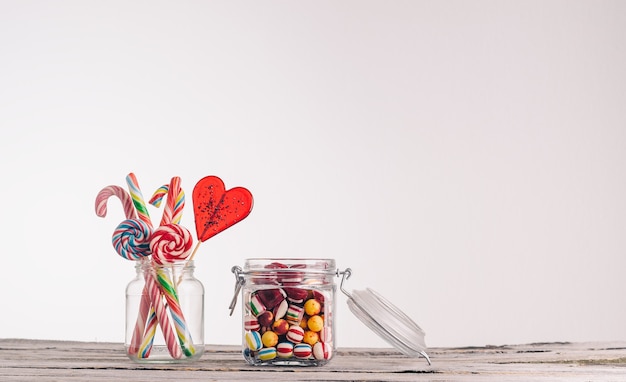 Gros plan de cannes de bonbon et autres bonbons dans des bocaux en verre sur une surface en bois