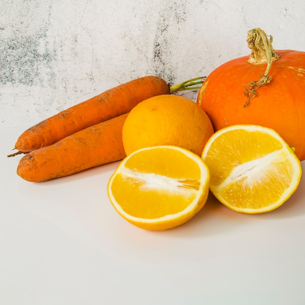 Gros plan de carotte; citrouille et oranges coupées en deux sur un vieux fond texturé