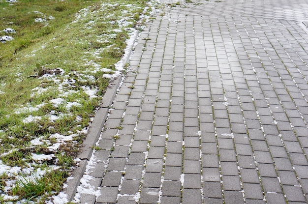 Gros plan sur une chaussée en pierre faite de blocs à côté de l'herbe en hiver