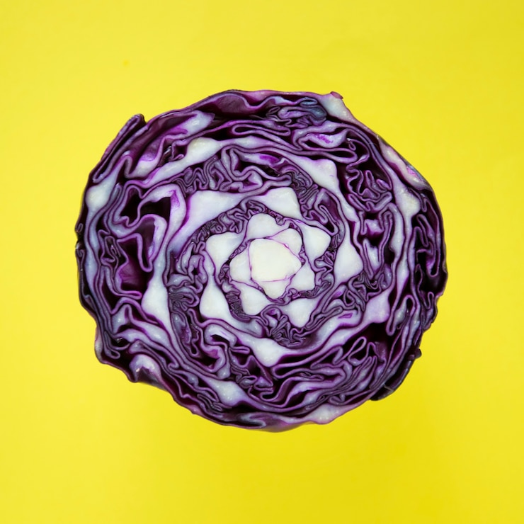 Photo gratuit gros plan de chou rond violet coupé en deux dans un fond jaune