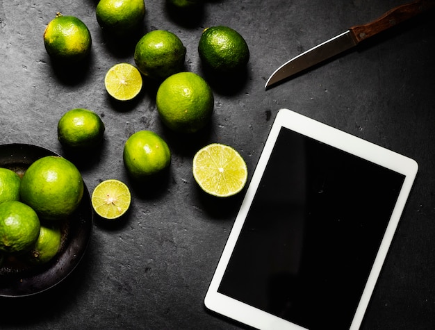 Gros plan de citron vert frais avec tablette numérique
