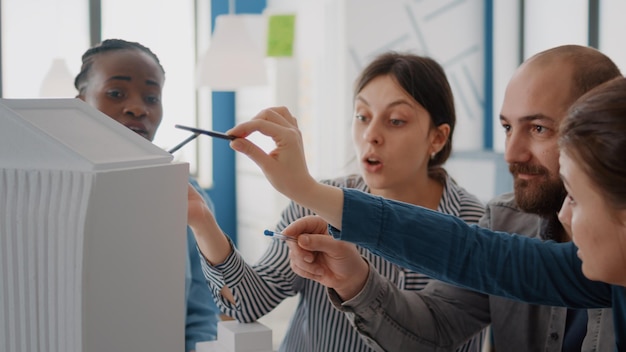 Photo gratuite gros plan sur des collègues de travail analysant le modèle de construction et la maquette sur table pour concevoir la construction. groupe de collègues divers travaillant sur un projet d'architecture pour la structure et le développement.