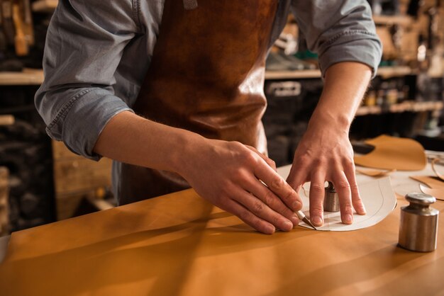 Gros plan d'un cordonnier coupe de cuir