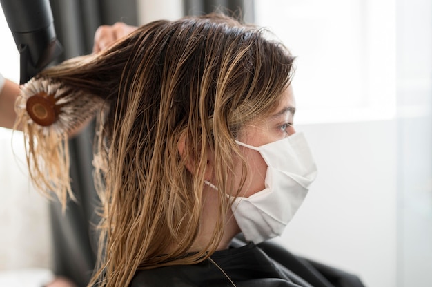 Photo gratuite gros plan sur le côté client au salon de coiffure portant un masque médical