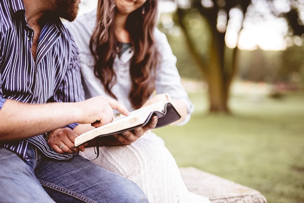 Photo gratuite gros plan d'un couple assis et lisant la bible