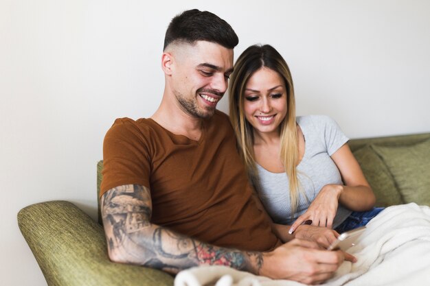 Gros plan, couple, séance, sofa, regarder, téléphone portable