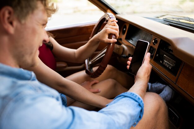 Gros plan couple en voiture avec smartphone