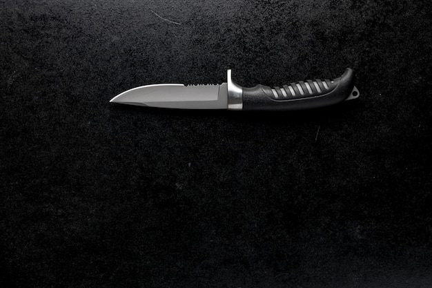 Photo gratuite gros plan d'un couteau tranchant fixe sur une table noire