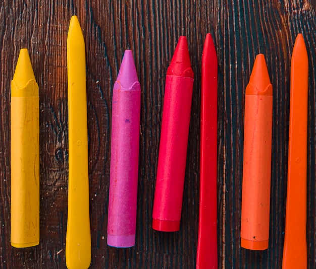 Gros plan de crayons de cire colorés sur une planche texturée en bois