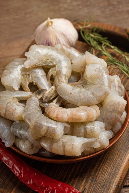 Gros plan de crevettes crues sur fond en bois.