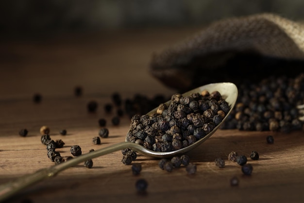 Gros plan d'une cuillère de graines de poivre noir sur la table