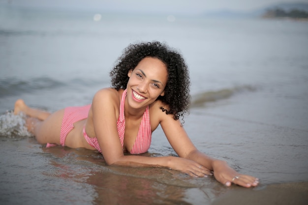 Gros plan d'une dame aux cheveux noirs couchée sur la plage en maillot de bain