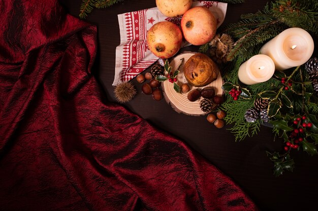 Gros plan d'une décoration de Noël avec des bougies branche de pin cônes fruits et panettone