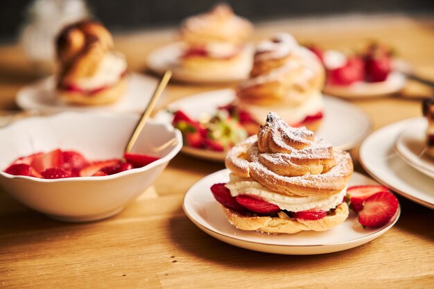 Gros plan de délicieux choux à la crème aux fraises sur une table en bois