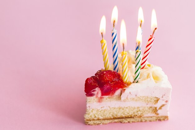 Gros plan d&#39;un délicieux et délicieux morceau de gâteau d&#39;anniversaire délicieux aux nombreuses bougies. Concept de vacances d&#39;anniversaire.