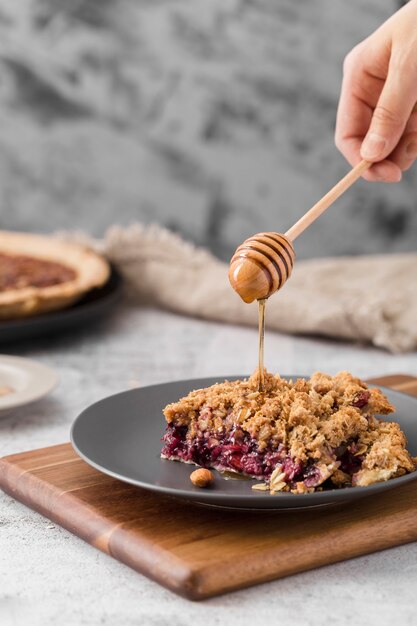 Gros plan délicieux morceau de tarte à la main avec du miel