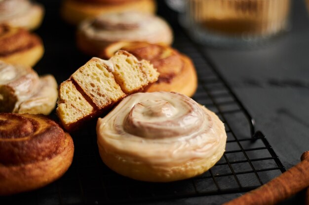 Gros plan de délicieux petits pains à la cannelle avec glaçage blanc sur un tableau noir