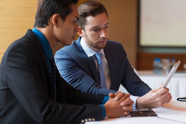 Gros plan de deux hommes d&#39;affaires sérieux utilisant la tablette