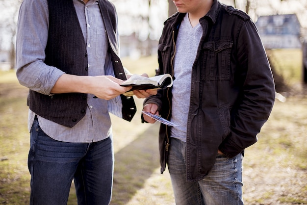 Photo gratuite gros plan de deux hommes debout près l'un de l'autre et lisant la bible