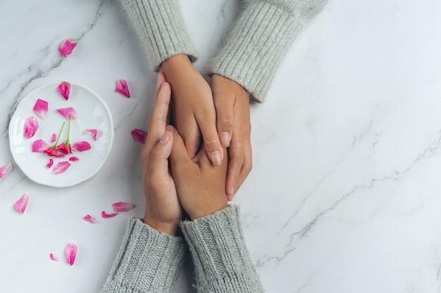 Gros plan sur deux jeunes amoureux se tenant la main à une table.