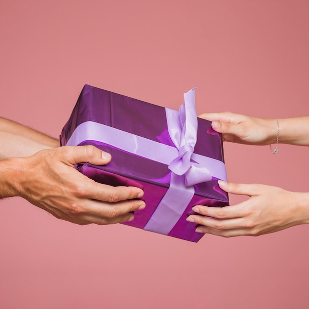 Gros plan, de, deux mains, tenue, violet, boîtes cadeau, contre, arrière-plan coloré
