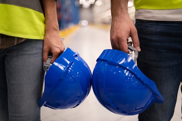 Photo gratuite gros plan de deux ouvriers industriels méconnaissables tenant des casques de protection