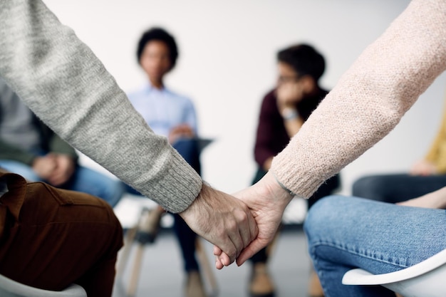 Gros plan de deux personnes se tenant la main pendant la thérapie de groupe