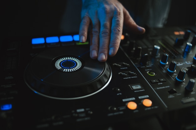 Photo gratuite gros plan d'un dj travaillant sous les lumières colorées dans un studio avec un flou