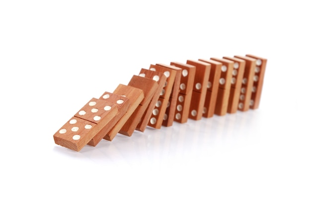 Gros plan des dominos en bois tombant sur une surface blanche