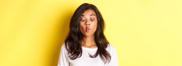 Photo gratuite gros plan d'une drôle de femme afro-américaine faisant des grimaces plissant les yeux et faisant la moue en s'amusant sur le jaune