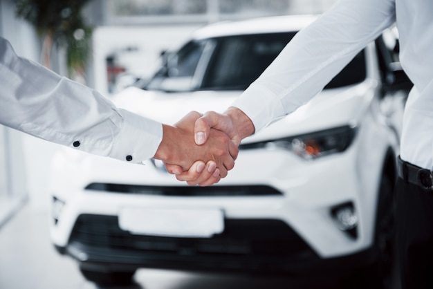 Gros plan du directeur des ventes en costume noir vendant la voiture au client