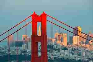 Photo gratuite gros plan du golden gate bridge avec le centre-ville de san francisco au coucher du soleil.