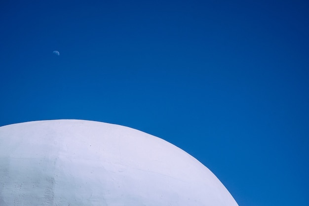 Gros plan du haut du bâtiment rond en béton blanc avec un ciel bleu clair en arrière-plan