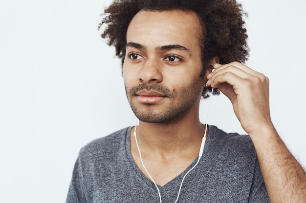 Gros plan du jeune homme africain, écouter de la musique dans les écouteurs.