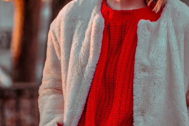 Gros plan du pull rouge et veste duveteuse blanche