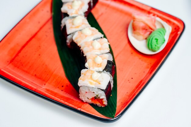 Gros plan du sushi nori recouvert de crevettes, sur fond blanc