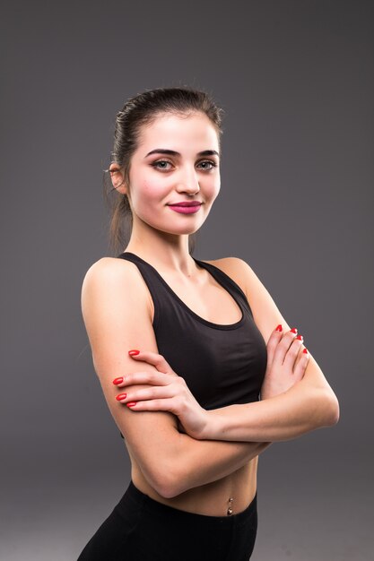 Gros plan du torse de la femme en forme avec ses mains sur les hanches sur le mur gris